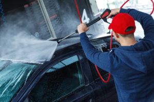 Professional car wash worker is washing client's car