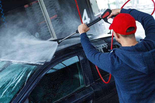 Professional car wash worker is washing client's car
