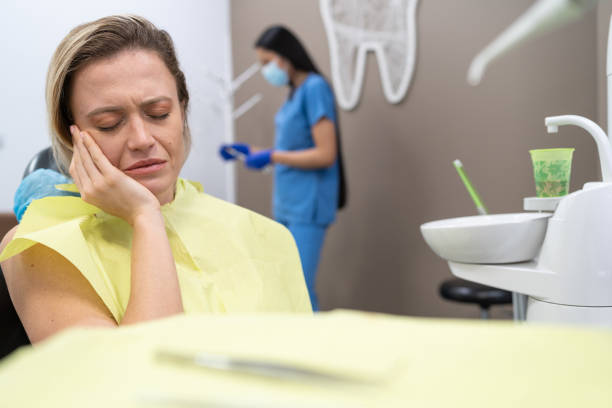 Woman suffering from toothache, sitting in dental chair at the clinic
